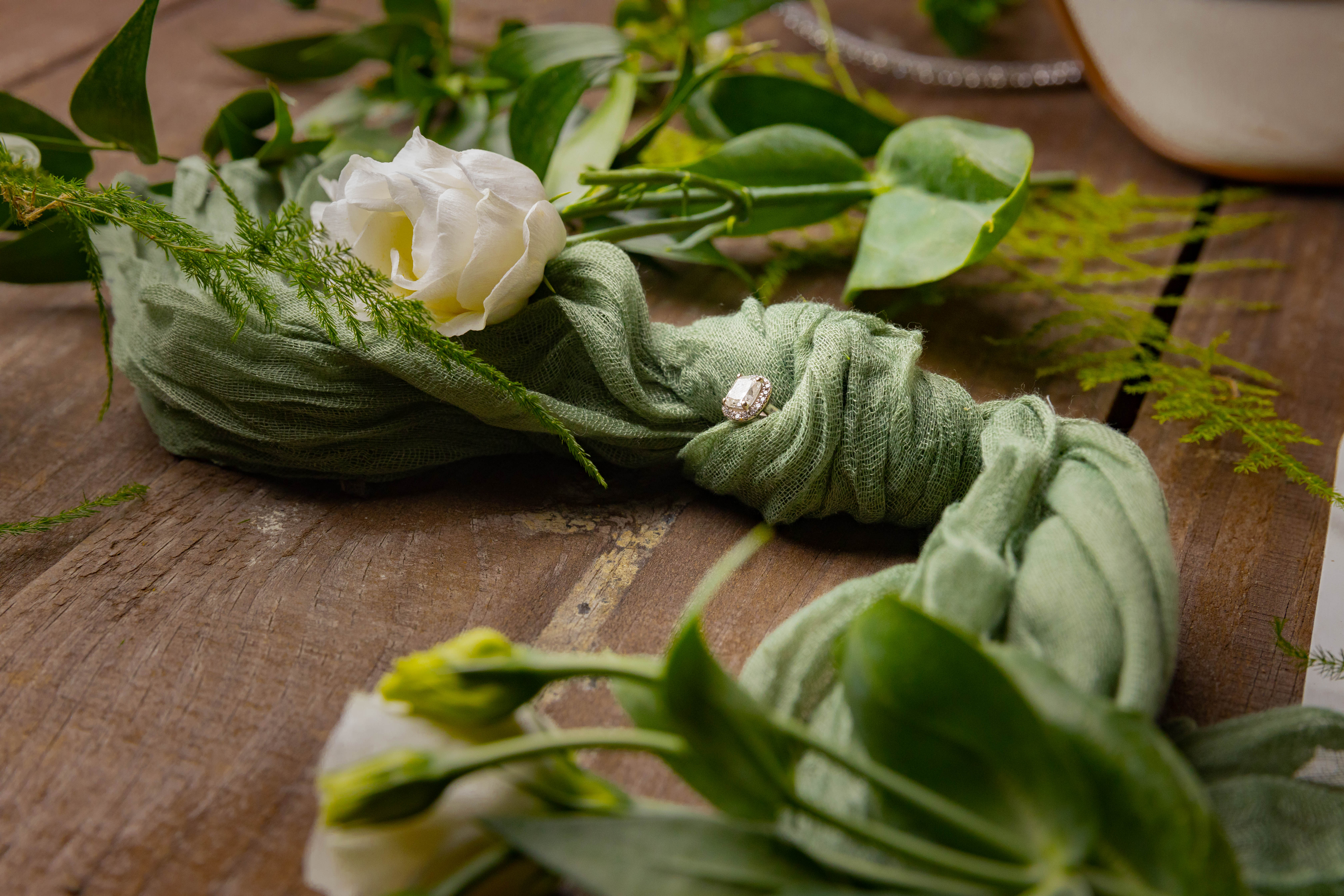 Green floral flat-lay — draped fabric, leaves, and white blossoms