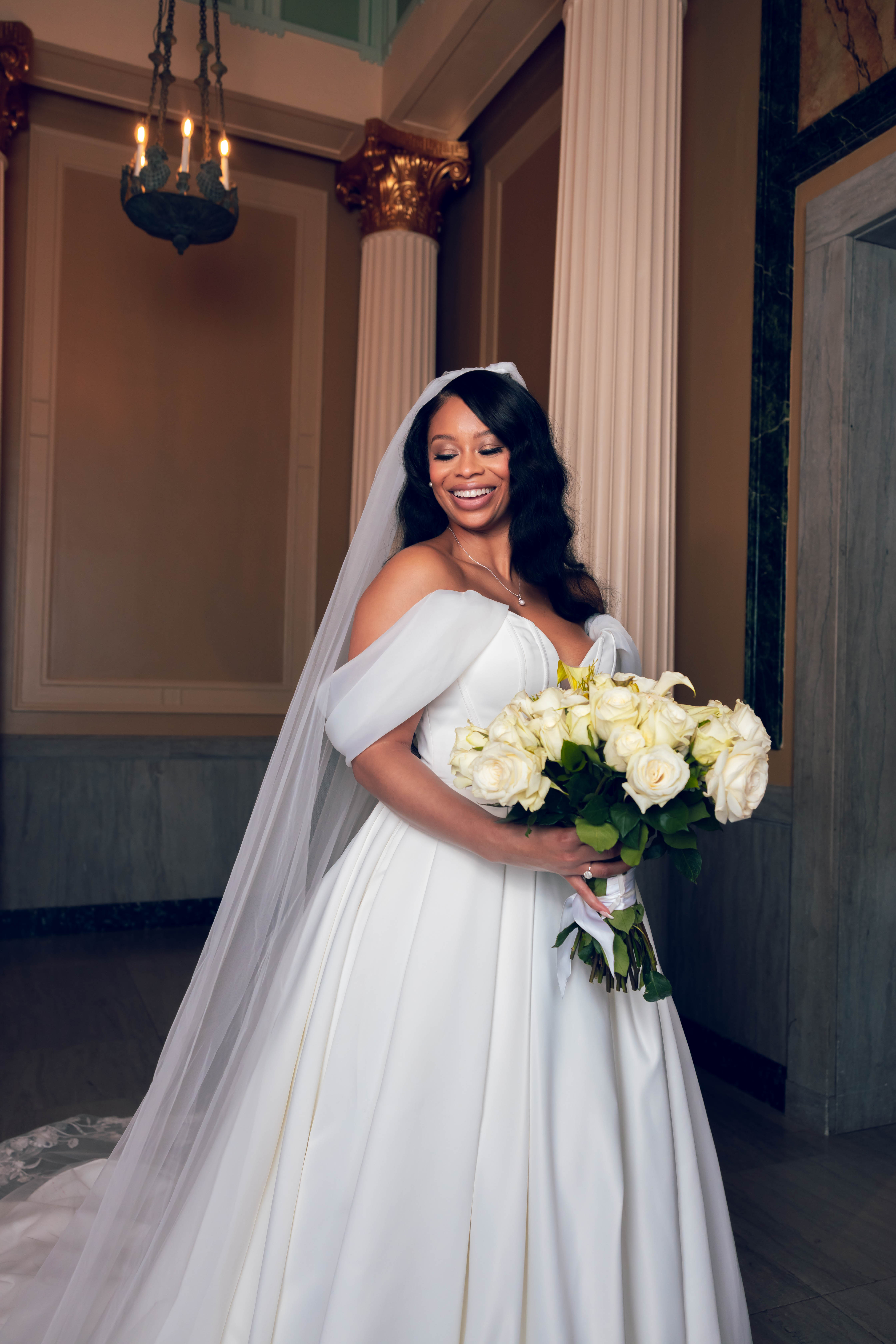 Vertical cinematic bride — full-length portrait with bouquet and chandelier depth